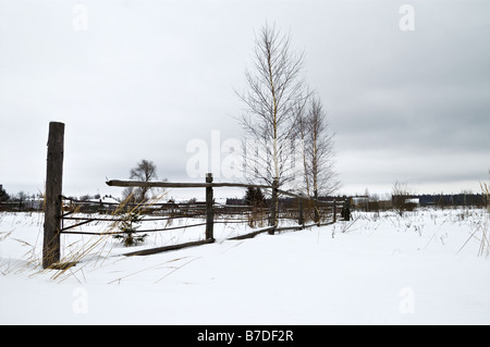 Paysage d'hiver avec clôture et un petit village dans l'arrière-plan Banque D'Images