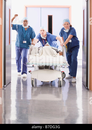 Trois médecins poussant un patient in bed Banque D'Images