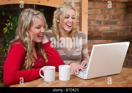 Deux belles jeunes femmes à la maison à l'aide d'un ordinateur portable ensemble Banque D'Images