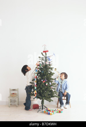 Les enfants décorer un arbre de Noël Banque D'Images