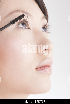 Woman putting on mascara Banque D'Images