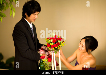 Jeune homme donnant un bouquet de fleurs à la jeune femme dîner aux chandelles Banque D'Images