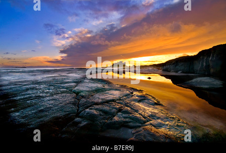 Le lever du soleil sur la plage et Château de Bamburgh castle sur la côte de Northumberland Banque D'Images