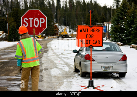 Un travailleur de la construction peut être vu tenant un panneau d'arrêt dans le Yellowstone. Banque D'Images