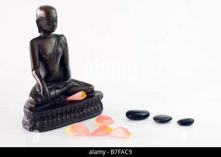 Bouddha avec des pétales de rose et de trois pierres noires Banque D'Images