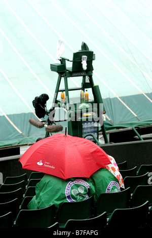 La pluie s'abat sur les parapluies de spectateurs en attente de lecture pour reprendre à Wimbledon Centre Court s Banque D'Images