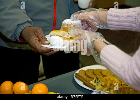 Les bénévoles servent le petit déjeuner pour les hommes sans-abri Banque D'Images