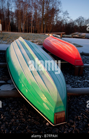 Barques en fibre de verre à haut retourné rouge et vert , skiff , skiffs / canot / dinghies beached à Winter , Finlande Banque D'Images