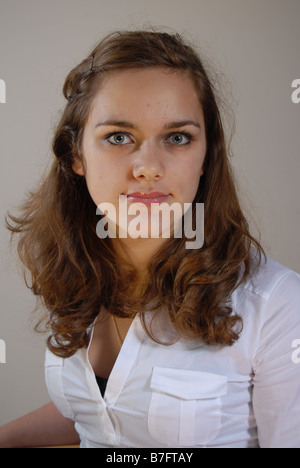 Jolie Adolescente portant un haut blanc avec des cheveux brune Assis Banque D'Images