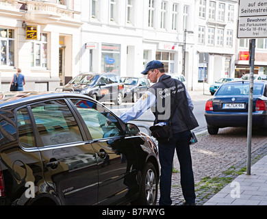 Directeur du trafic mettre billet sur voiture stationnée en Allemagne Lubeck rue Banque D'Images