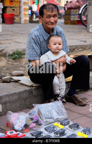 Un vieil homme chinois avec un jeune garçon chinois assis dans une rue de HoHot, la Mongolie intérieure, le nord de la Chine Banque D'Images