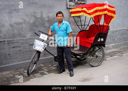 Un pousse-pousse et son opérateur de transport de touristes à travers les ruelles étroites et des rues de la Hutong, Beijing, Chine Banque D'Images