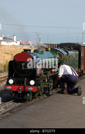 Un homme travaillant sur un train à vapeur miniature Banque D'Images