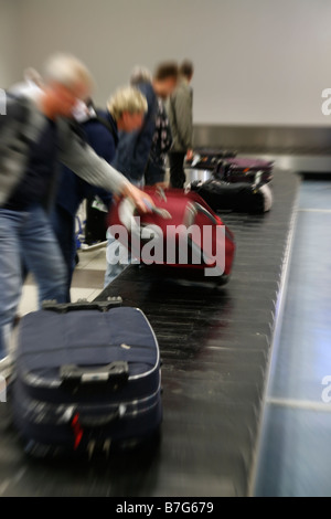 Les touristes obtenir leurs bagages à l'aéroport Banque D'Images