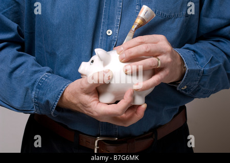 Un homme de mettre un billet en euros 50 dans une tirelire précieux Banque D'Images