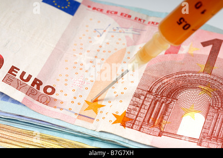 Stock photo d'un hyperdermic l'injection de l'aiguille sur un tas de billets un apport en numéraire Banque D'Images