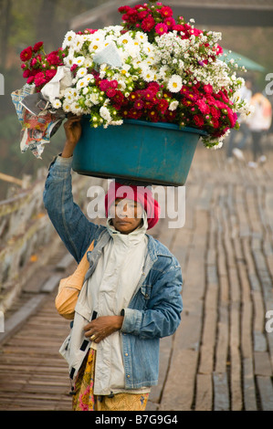 Mon femme avec panier de fleurs sur sa tête en bois traversant le pont en teck à Sangklaburi en Thaïlande Banque D'Images