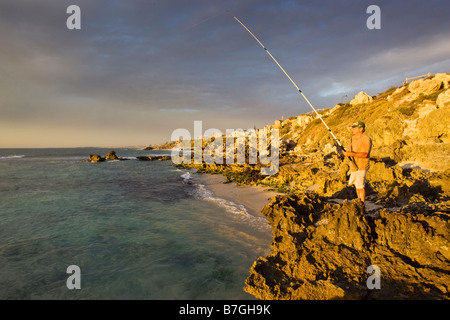 Un homme la pêche au large de la plage des roches à Trigg à Perth, Australie occidentale Banque D'Images