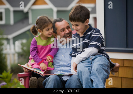 Père en fils et fille de lecture sur le porche Banque D'Images