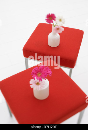 Les gerberas roses dans des vases sur des tabourets. Banque D'Images