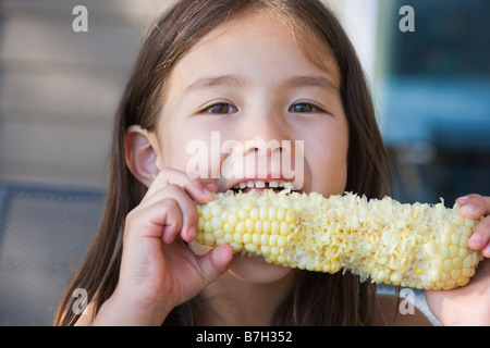 Asian girl eating corn on the cob Banque D'Images