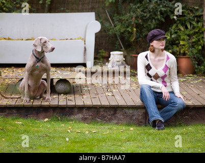 Femme et chien Weimaraner assis dans un jardin élégant Banque D'Images