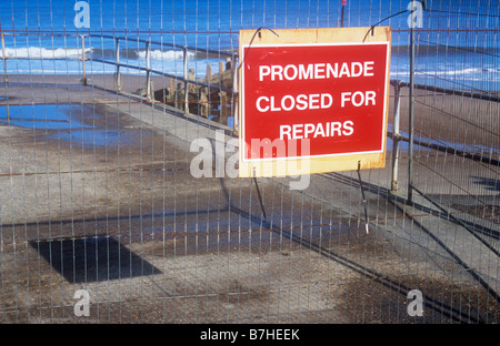 Promenade en béton au-dessus du sable avec des éperons et de la mer avec du fil de grillage de séparation et l'avis Promenade fermée pour travaux Banque D'Images