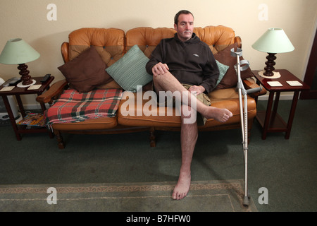 Un portrait d'un homme avec une cheville cassée assis sur une chaise dans sa chambre et a été immobilisé pendant plus de 13 mois d'attente pour Banque D'Images