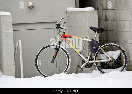 Un vélo stationné à l'extérieur d'une porte dans la neige Banque D'Images