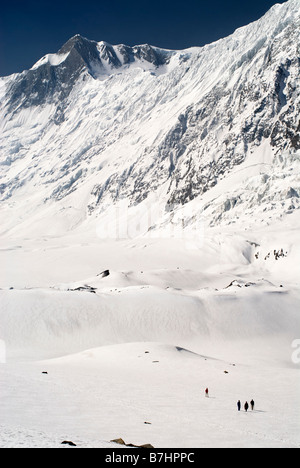 Quatre randonneurs à pied sur la neige au-dessous de Tilicho Peak sur l'approche de Tilicho Lake. Les montagnes de l'Annapurna, Népal Banque D'Images