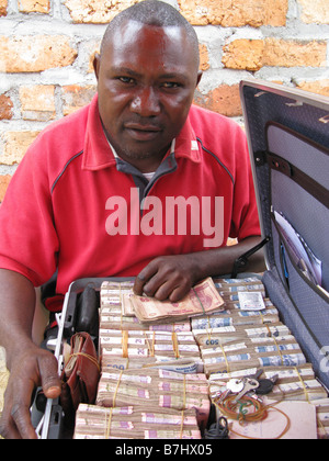 Changeur de monnaie avec cas pleine de Francs congolais assis à table sur la rue de Kisagani République démocratique du Congo Banque D'Images