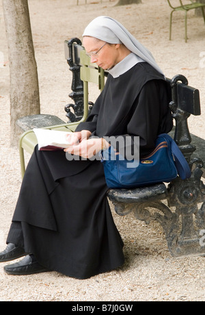 Une religieuse assise sur un banc pour lire un livre dans le Jardin du Luxembourg à Paris, France Europe Banque D'Images