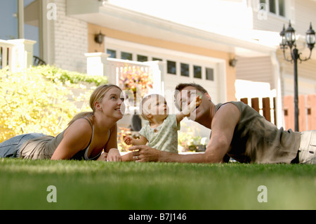 Jeune homme & femme jouant avec bébé dans l'herbe, Regina, Saskatchewan Banque D'Images