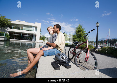 Jeune couple reste à partir de la bicyclette à la fontaine, vue latérale, Vancouver, Colombie-Britannique Banque D'Images