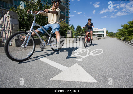 Jeune couple de la bicyclette sur la piste cyclable de la ville, Vancouver, Colombie-Britannique Banque D'Images