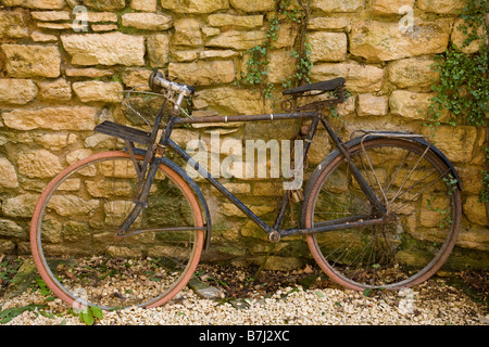 Un très vieux vélo rouillé un peu façon incongrue enchaînés à un mur, Sarlat, France. Banque D'Images