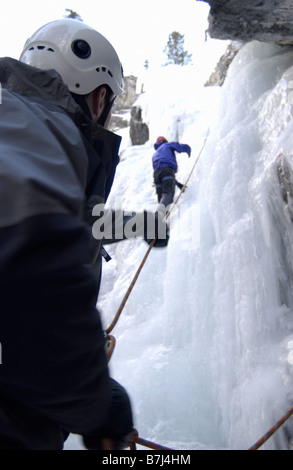 Deux hommes (20-25) L'escalade sur glace. L'un des grimpeurs relais l'autre comme mesure de sécurité. Canmore, Alberta, Canada Banque D'Images