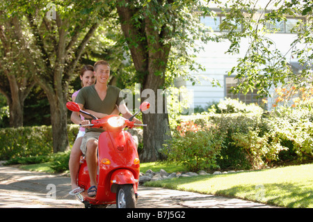 Teenage boy and girl driving red vespa, Regina, Saskatchewan Banque D'Images