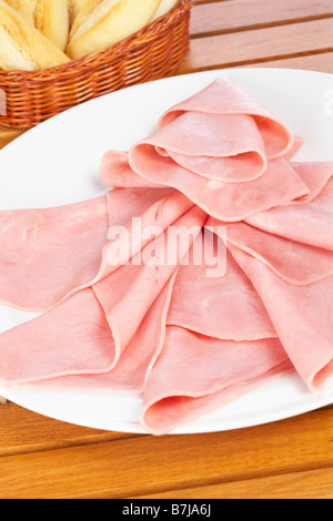 Tranches de jambon sur un plat savoureux blanc et du pain dans le panier profondeur de champ Banque D'Images