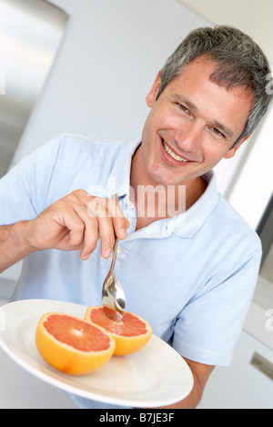 Middle aged Man Eating pamplemousses frais Banque D'Images