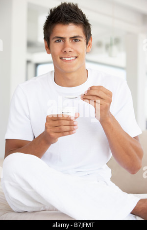 Young Man Eating Yoghurt Banque D'Images