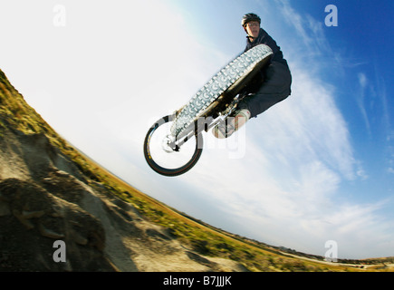 Fish Eye low angle view of mountain biker jumping ; Canada, Alberta, Calgary Banque D'Images