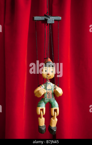 Marionnette en bois Pinocchio est en face du rideau rouge Banque D'Images