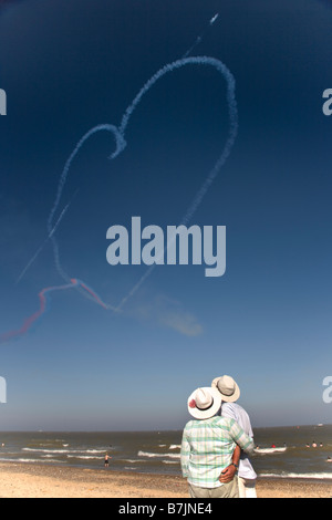 Couple de personnes âgées en tenir une autre avec des flèches rouges coeur dans le ciel derrière eux Banque D'Images