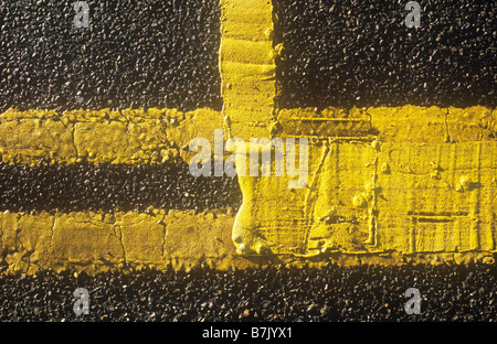 Détail du dessus de la lumineuse chambre double lignes jaunes sur le bord de la route avec la peinture jaune supplémentaire appliquée en couche épaisse pour créer fort Banque D'Images