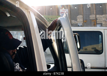 Les chauffeurs de taxi attendent le long du mur de séparation qui coupe la ville cisjordanienne de Al-Ram en deux. Banque D'Images