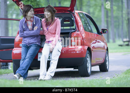 Jeune couple assis sur le tronc du véhicule et le chat Banque D'Images