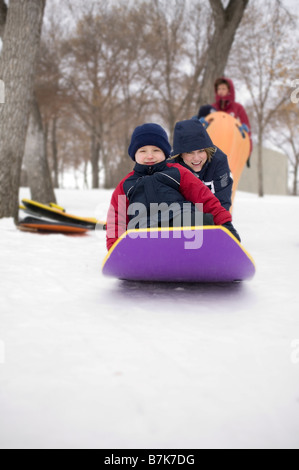 Gril pousse un autre enfant sur le toboggan, Regina, Saskatchewan, Canada Banque D'Images
