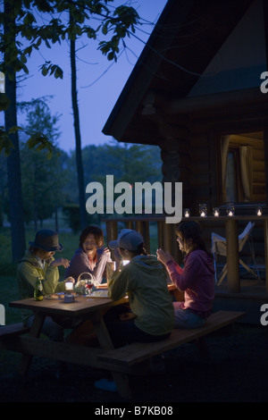 Groupe de jeunes conversent sur Camping au début de la nuit Banque D'Images