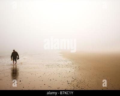 Homme marchant le long beach dans le brouillard Banque D'Images